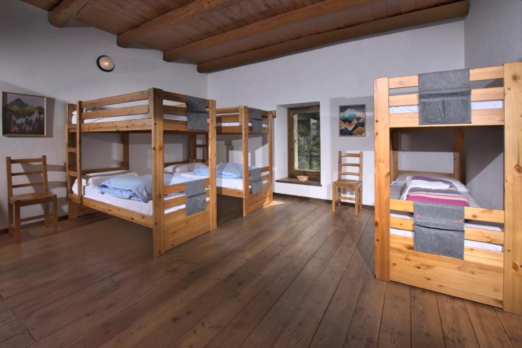 a room with three bunk beds in a house at Rifugio Escursionistico La Ruà in Macra