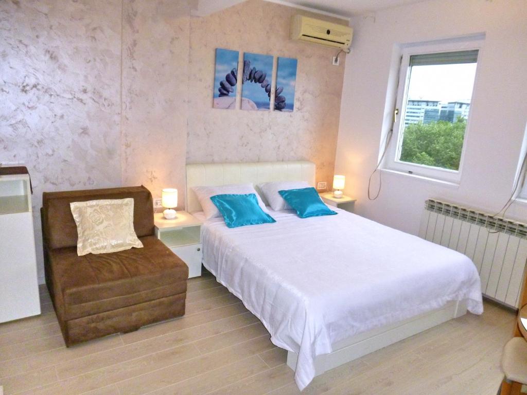 Un dormitorio con una cama con almohadas azules y una silla en Arena Dream Studio, en Belgrado