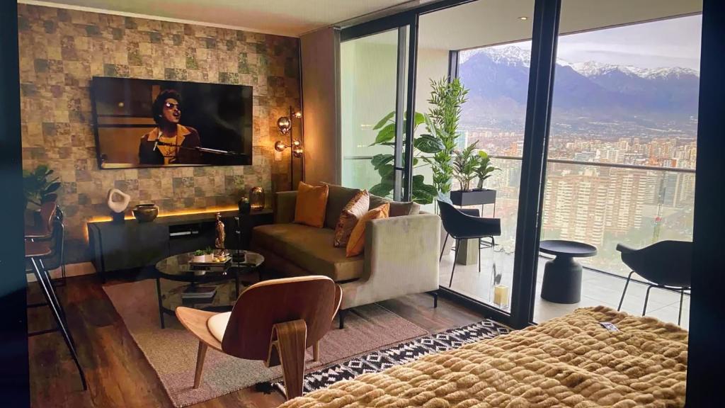 een woonkamer met een bank en een tv aan de muur bij Departamento de lujo en suite, en el piso 38, Las Condes, costado de parques y malls in Santiago