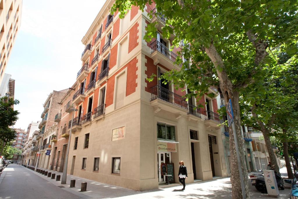 バルセロナにあるAPBCN アシャンプラ センターの建物前の通りを歩く女