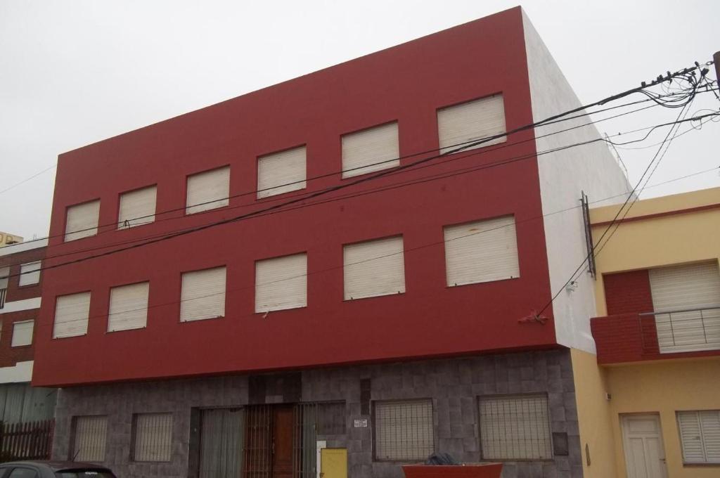 un edificio rosso con finestre bianche sul lato di Mutualidad de empleados del Club Gimnasia y Esgrima de Buenos Aires a Mar de Ajó