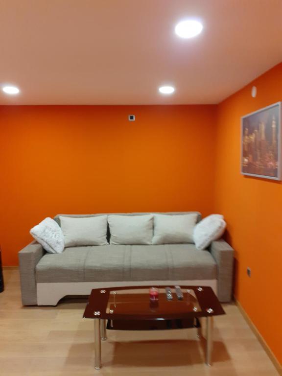 - un salon avec un canapé et un mur orange dans l'établissement MAJA, à Velika Gorica