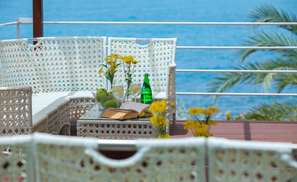 a table with a book and flowers on a balcony at Queens Bay Hotel in Paphos