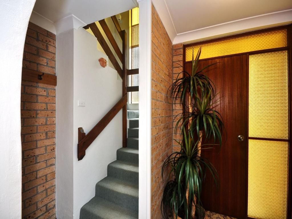 a staircase in a house with a brick wall at Close To The Main Surf Beach in Hawks Nest
