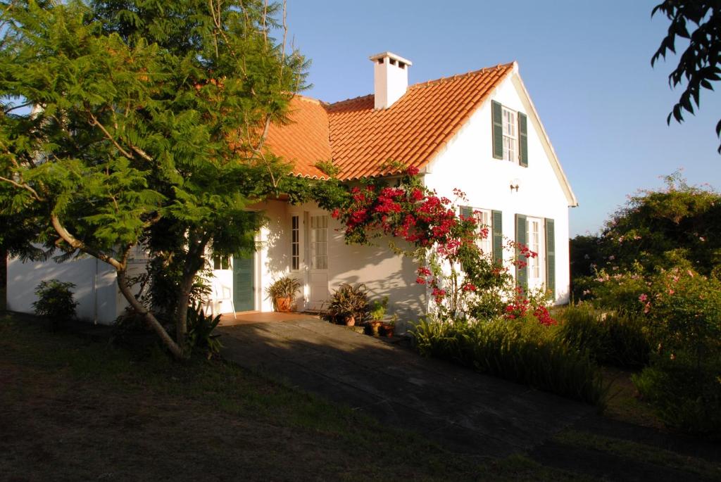 a white house with flowers on the side of it at Casa do Areal in São Roque do Pico