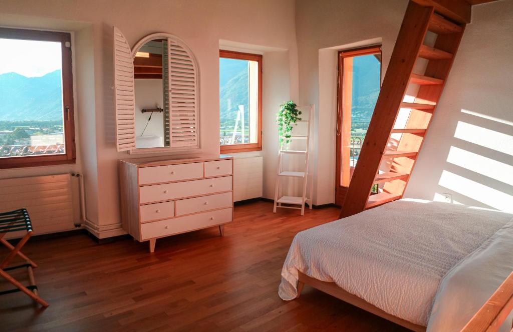 a bedroom with a bed and a dresser and windows at Wisteria House - Holiday Apartment in Cadenazzo