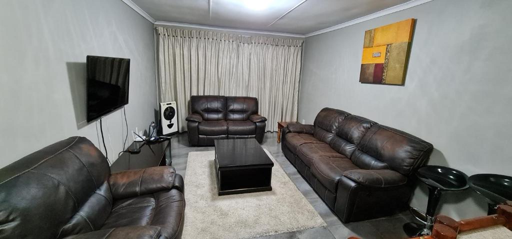 sala de estar con muebles de cuero y TV de pantalla plana en Executive 2 bed Apartment, free WIFI and DSTV, en Johannesburgo