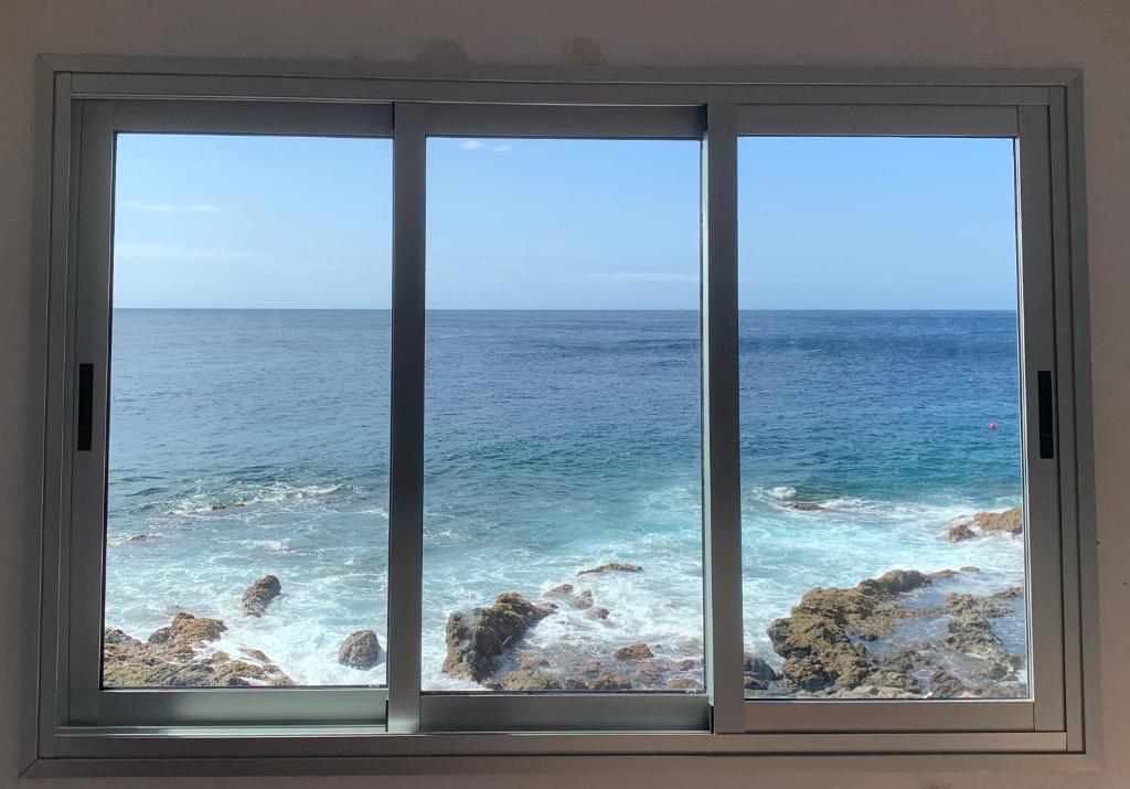 a window with a view of the ocean at Maravillosas vistas al mar "Primera Línea" Apartamentos Can Toca - Seahouses in Santa Cruz de Tenerife
