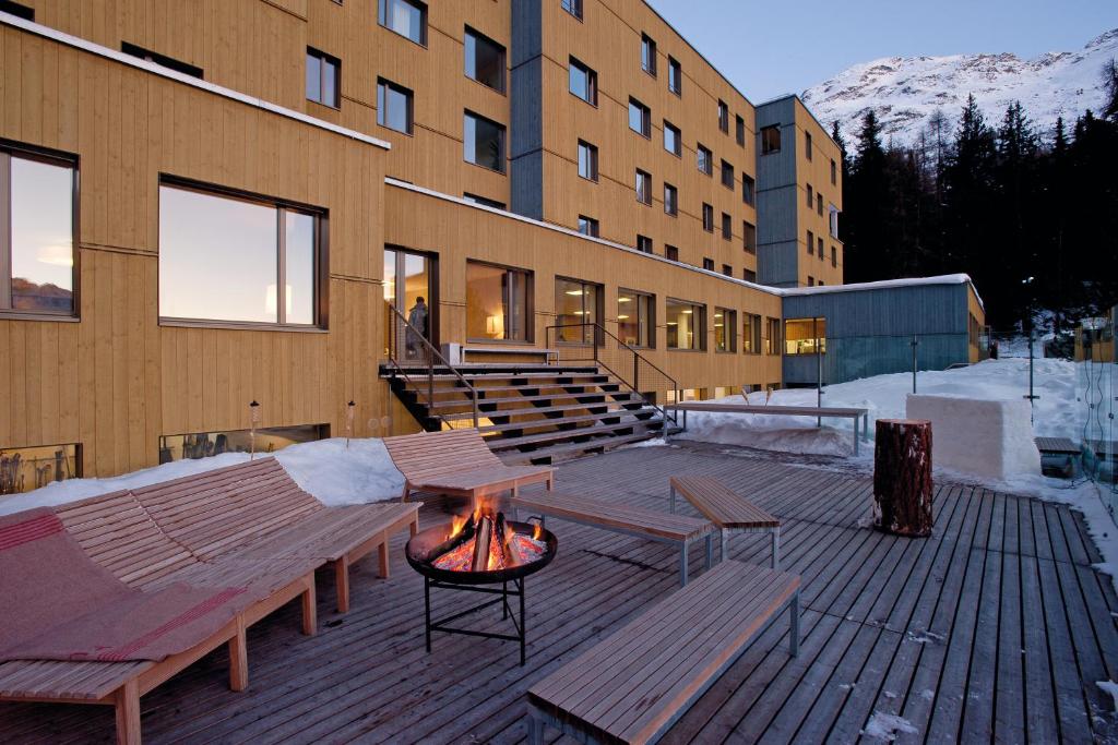 a patio area with chairs, tables, and a building at St. Moritz Youth Hostel in St. Moritz