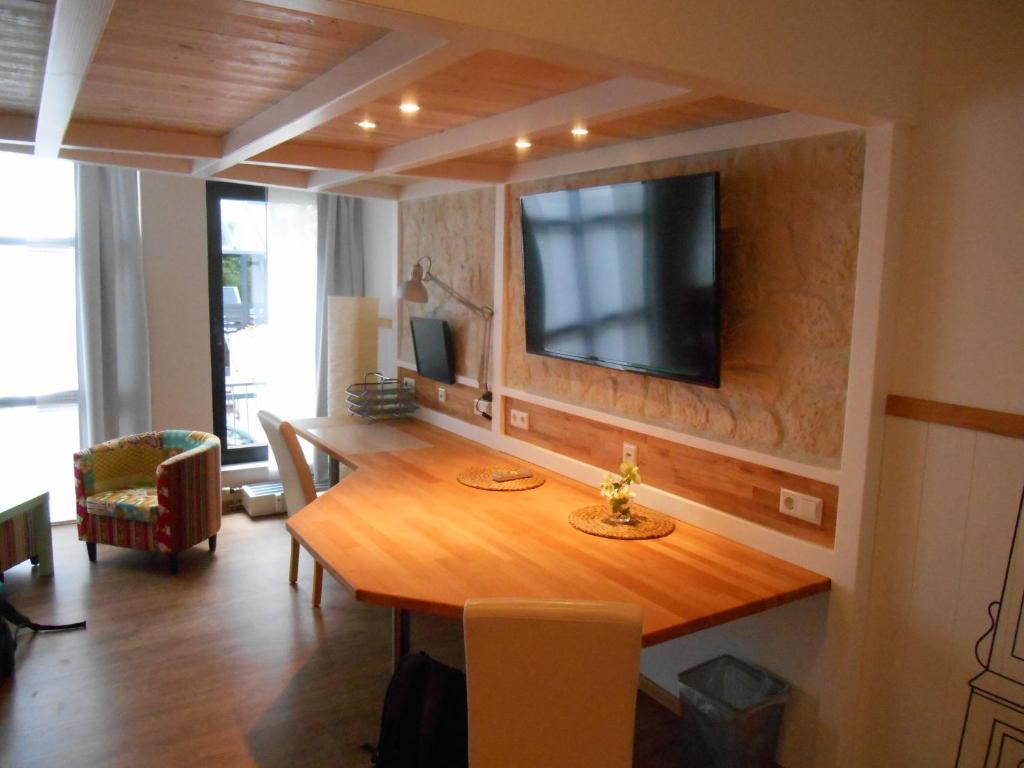 a living room with a wooden table and a television on a wall at Warum ins Hotel in Neckarsulm