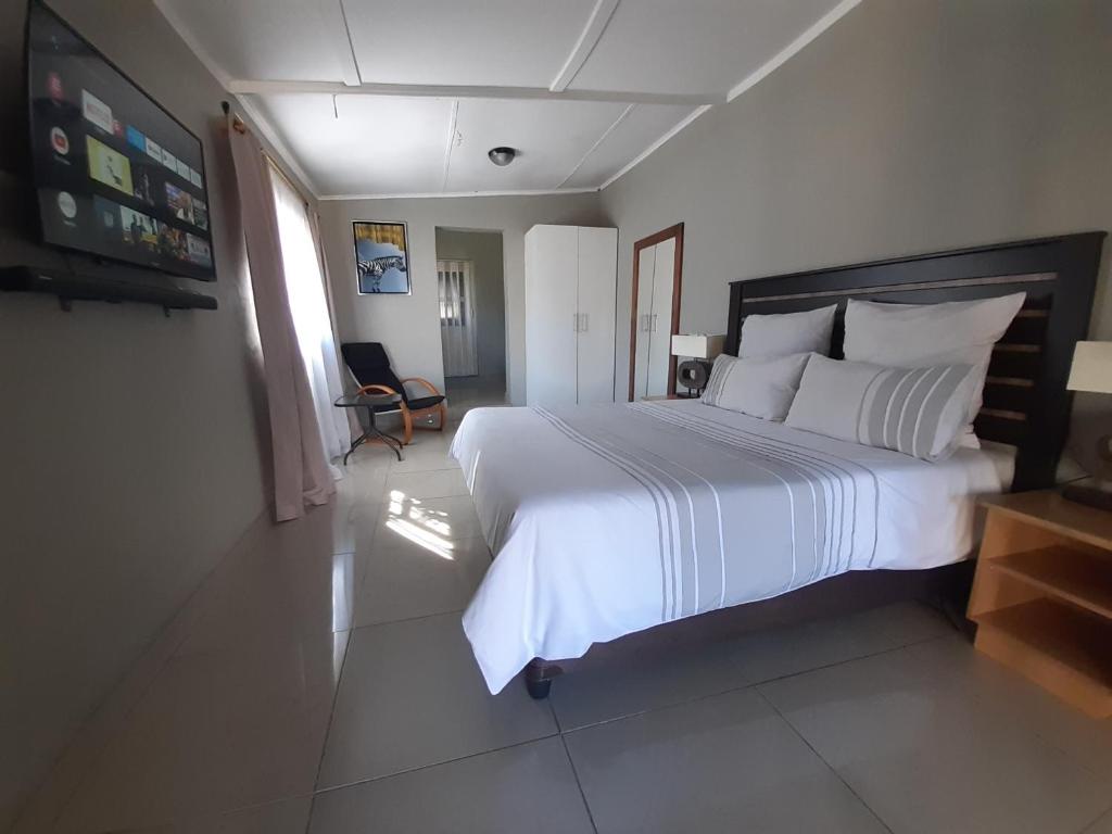 una camera da letto con un grande letto con lenzuola e cuscini bianchi di The Private and Cosy Guest House 2 a Germiston