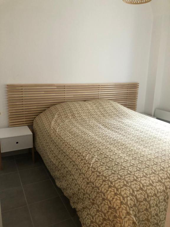 a bedroom with a bed with a wooden headboard at Aldebaje in Le Tréport