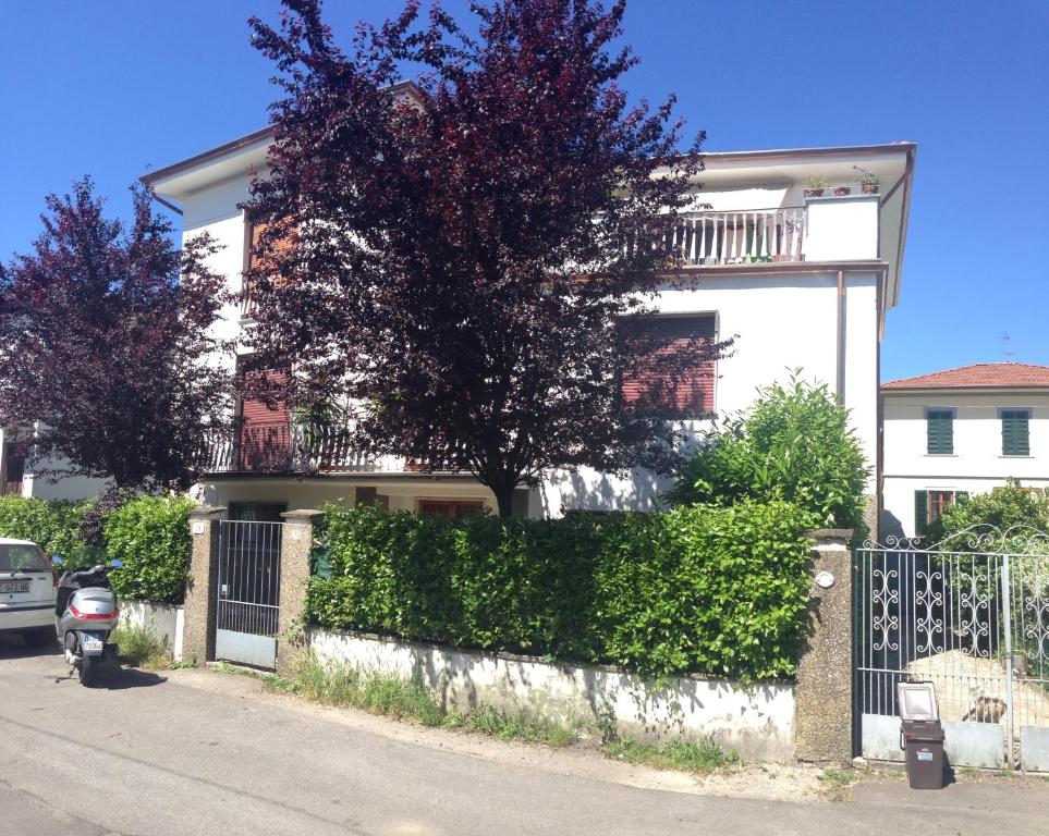 una casa blanca con un árbol delante de una valla en A Quattro Passi Dalle Mura, en Lucca
