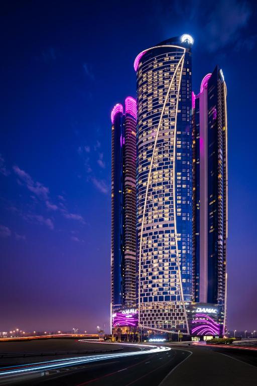 迪拜Paramount Hotel Dubai的一座高大的建筑,晚上有紫色的灯光