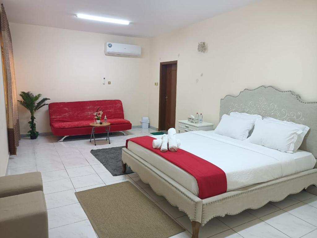 a bedroom with a large bed and a red couch at Residence villa 106 in Al Ain