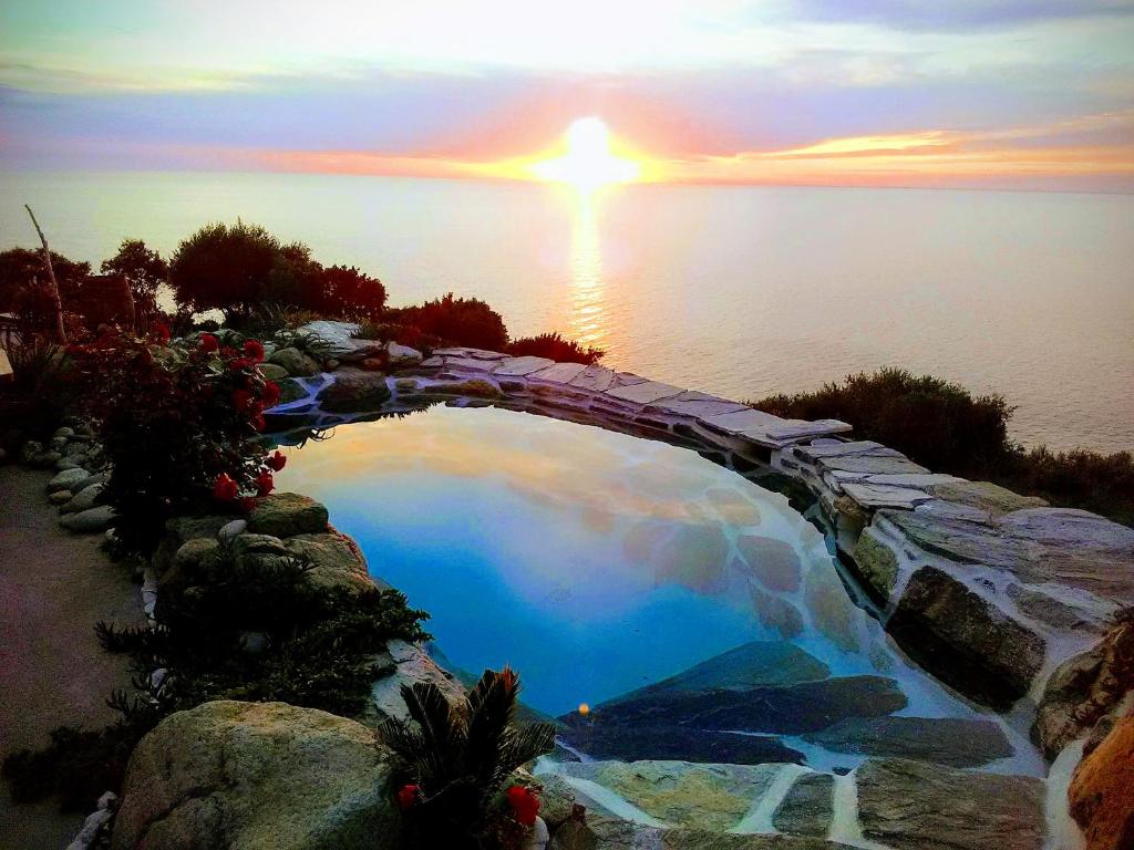 a pool of water with a sunset in the background at Maison de charme avec piscine et jacuzzi in Pino
