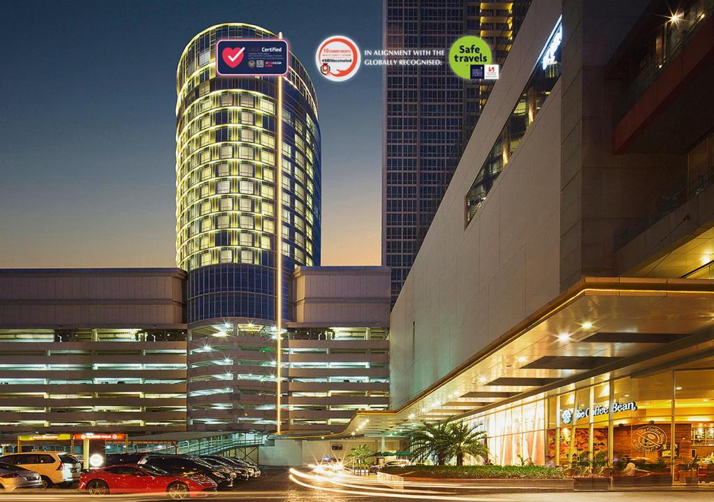 wysoki budynek z samochodami zaparkowanymi na parkingu w obiekcie Hotel Ciputra World Surabaya managed by Swiss-Belhotel International w mieście Surabaja