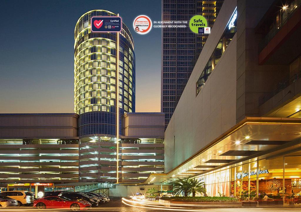 Hotel Ciputra World Surabaya managed by Swiss-Belhotel International في سورابايا: مبنى طويل وبه سيارات متوقفة في موقف للسيارات