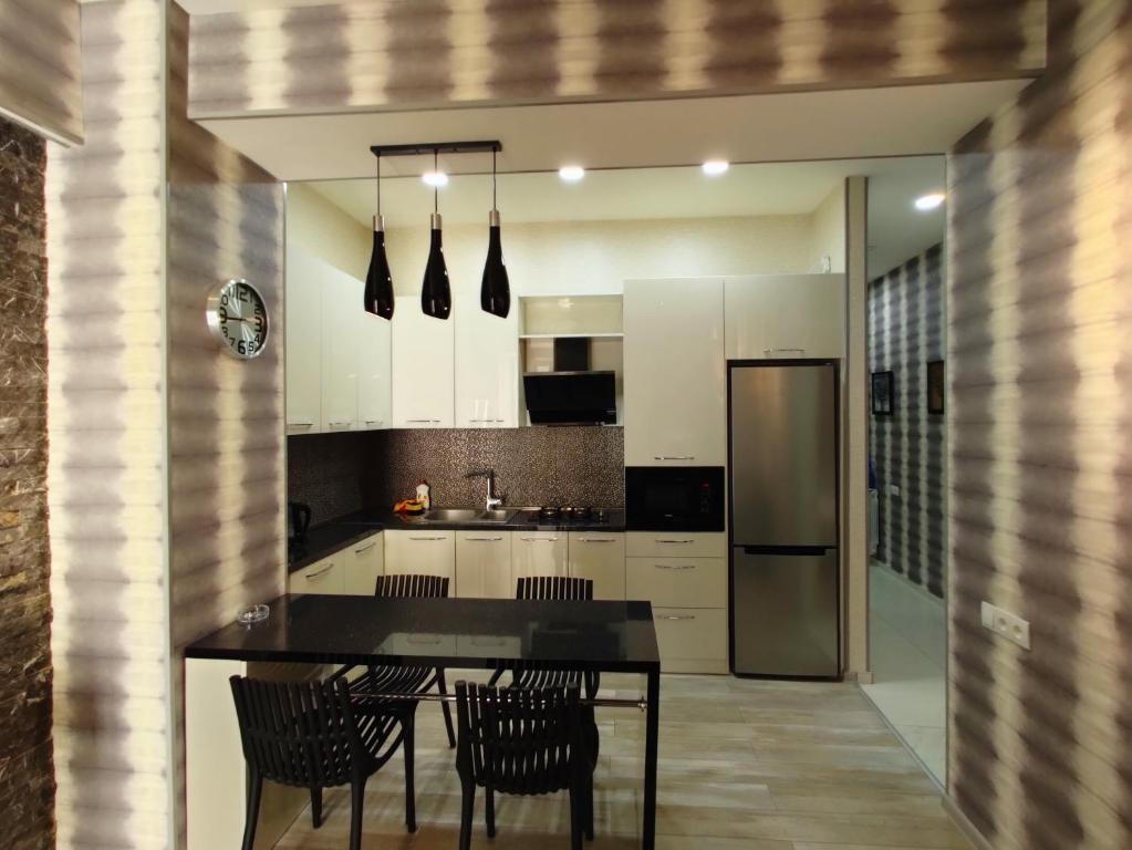 een keuken met een tafel en stoelen en een koelkast bij Tbilisi App 2 in Tbilisi City