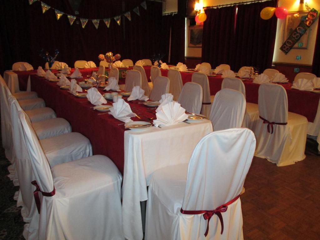 una fila de mesas con sillas blancas en una habitación en Old New Inn, Llanfyllin, en Llanfyllin