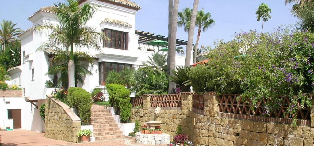 a white house with a stone wall and stairs at Beach and Golf Resort La Perla Miguel Adults Only in Marbella