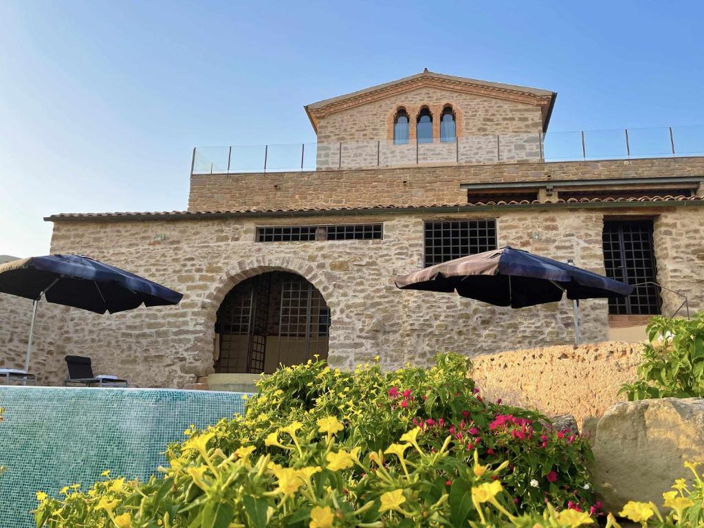 a building with two umbrellas and a swimming pool at Masia de Queralt Luxury Casa Rural Spa y Vistas in Concabella