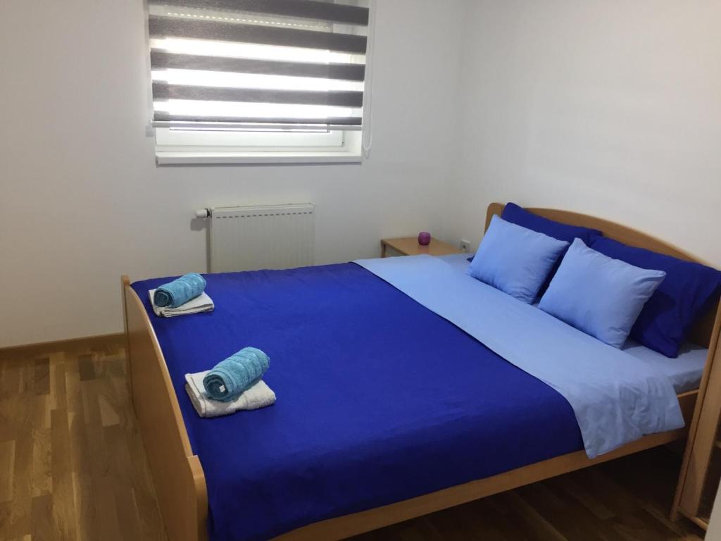 a bedroom with a bed with blue sheets and blue pillows at Apartman Tami in Doboj