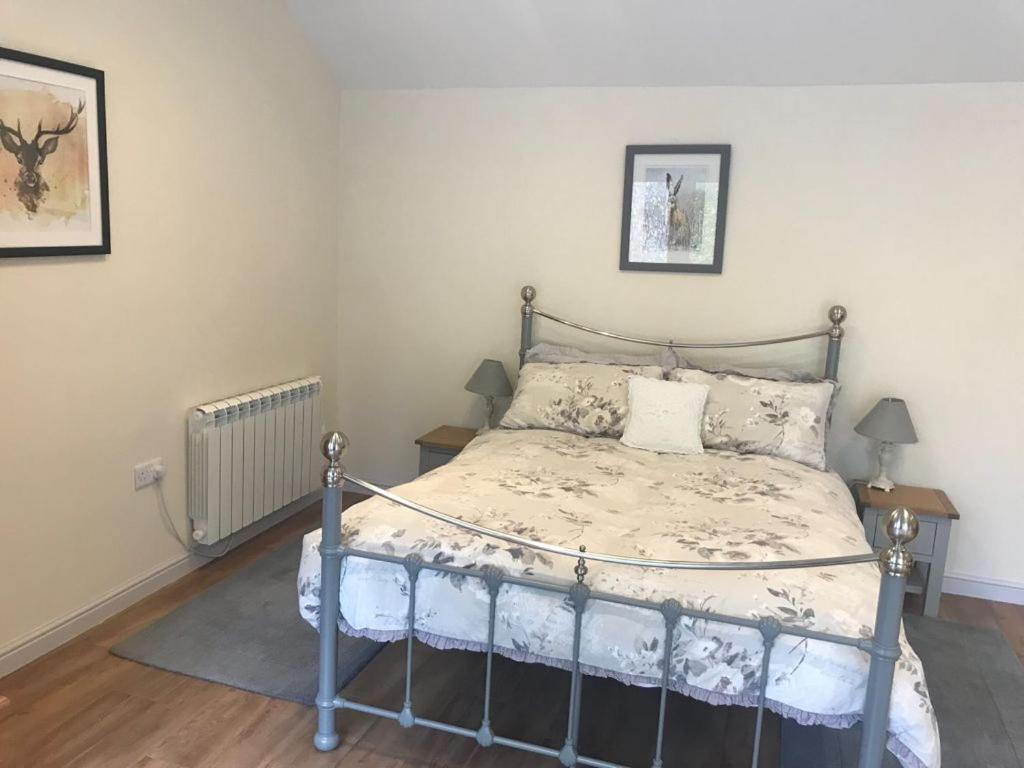1 dormitorio con 1 cama y 2 cuadros en la pared en Quantock House Lodge, en Holford