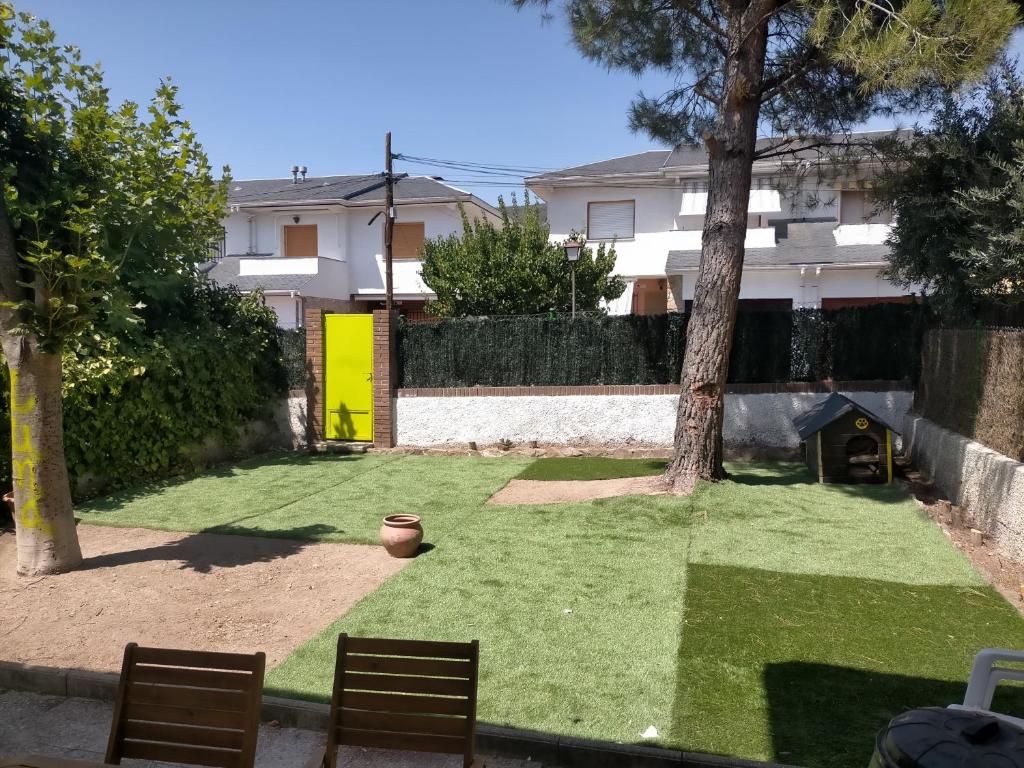 un pequeño patio con césped y un árbol en Chalet adosado con jardín, en Cebreros
