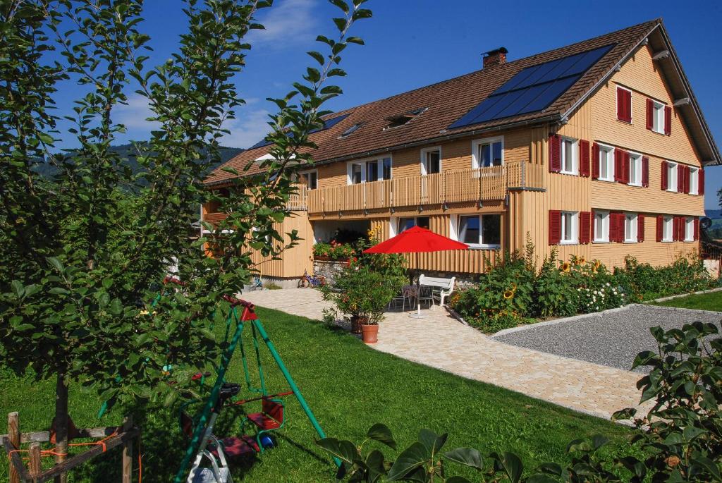 uma casa com painéis solares na lateral em Ferienwohnung Sonnenhof em Andelsbuch