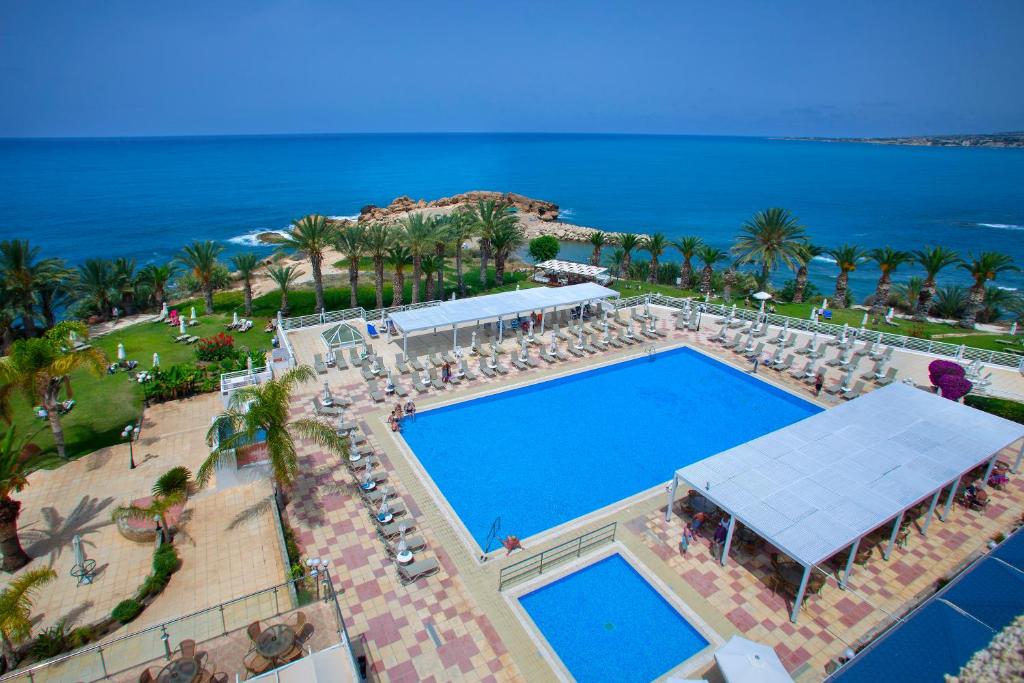 an overhead view of a swimming pool with chairs and the ocean at Queens Bay Hotel in Paphos