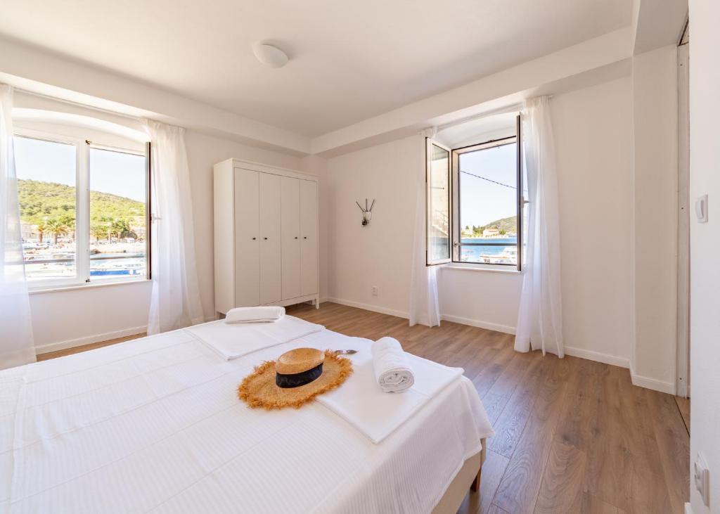 a white bedroom with two beds and two windows at Central Seaside Residence in Vis