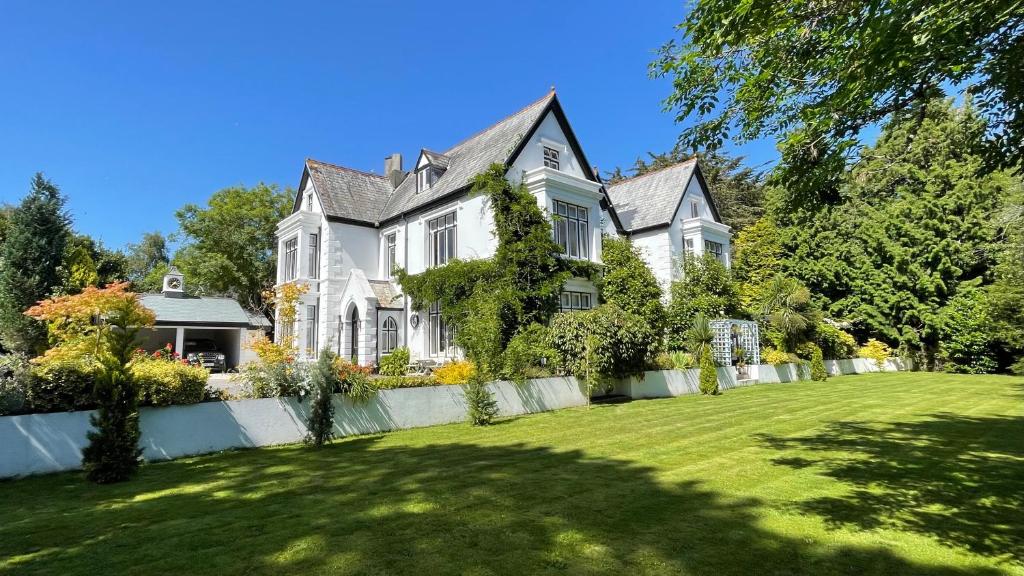 una gran casa blanca con una valla y un patio en Penarwyn House en Par