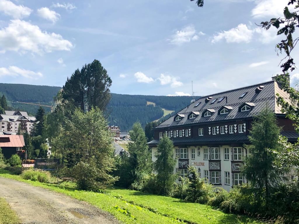 a building in a field next to a dirt road at Apartman Bellevue in Špindlerův Mlýn