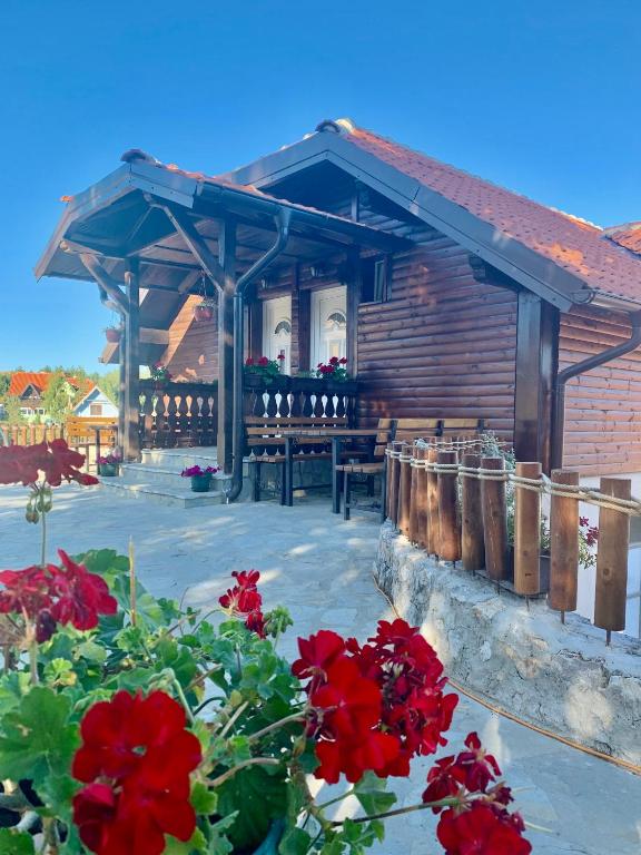 a wooden cabin with red flowers in front of it at Vila Zorica Vodice in Zlatibor