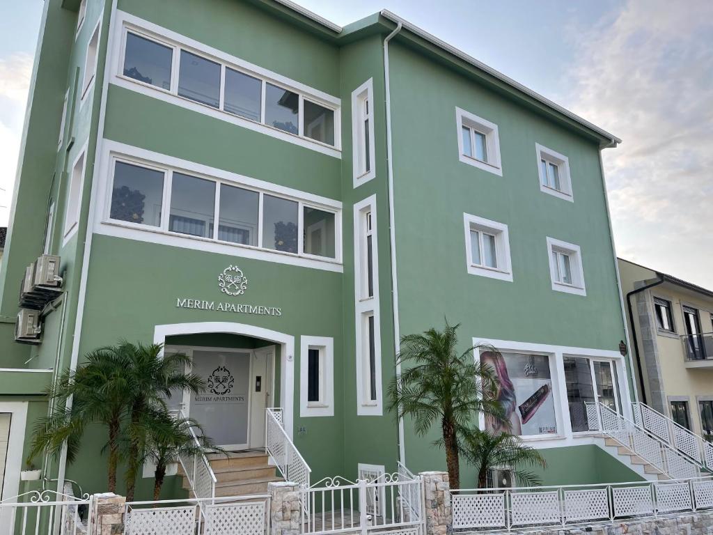 un bâtiment vert avec des palmiers devant lui dans l'établissement Merim Apartments, à Ponte de Lima