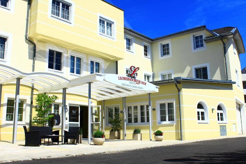 un edificio blanco y amarillo con un letrero. en Hotel Leobersdorfer Hof en Leobersdorf
