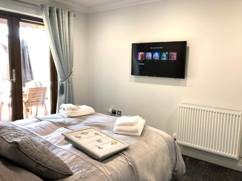 a room with a bed with a tv on the wall at Room on the River in Cruden Bay