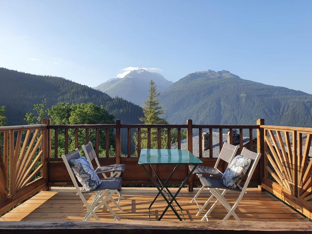 a table and chairs on a wooden deck with mountains at Le chalet de Flo in Séez