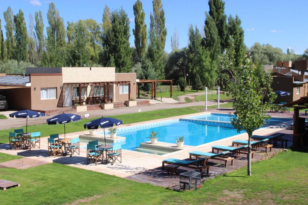 a swimming pool with tables and umbrellas next to a house at Cabañas Amalar in Malargüe