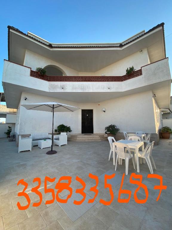 a patio with an umbrella and tables and chairs at Villa Vistasalentina Piano terra in Torre Colimena