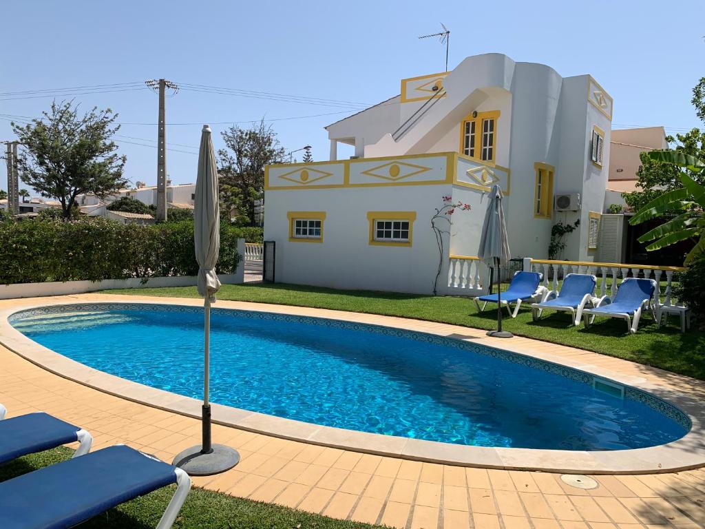 
a swimming pool with a blue chair and blue chairs at Villa Roja Pé in Albufeira
