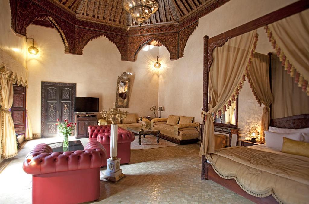 une chambre avec un lit à baldaquin et un salon dans l'établissement Palais Shéhérazade & Spa, à Fès