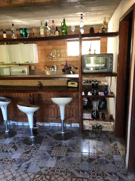 a kitchen with a bar with stools and a microwave at CASA RAIZ IBITIPOCA in Conceição da Ibitipoca