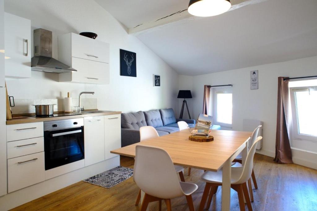 T3 cosy au centre de Castelnaudary في كاستيلنوداري: مطبخ وغرفة معيشة مع طاولة وكراسي خشبية