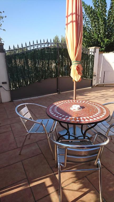 una mesa y sillas con una sombrilla en el patio en Le Tamaris en Saint-Laurent-dʼAigouze