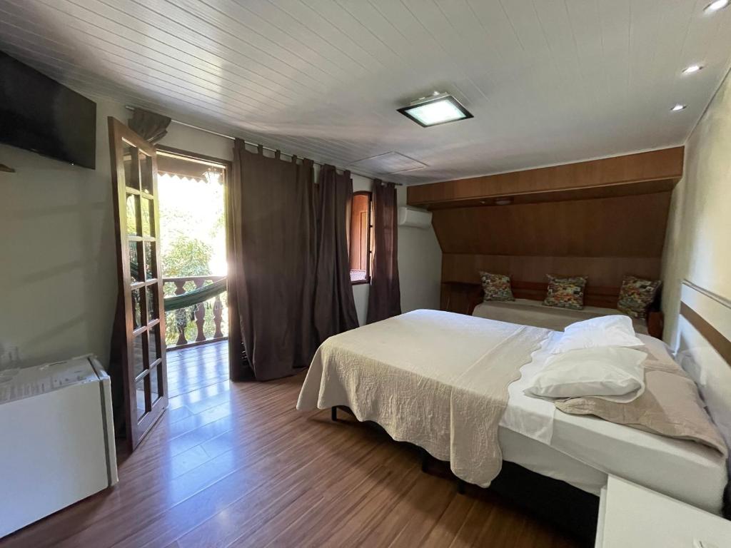 a bedroom with a large bed and a balcony at Chalé do Recanto in Lumiar