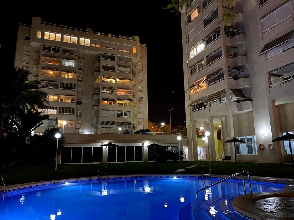 una piscina frente a dos edificios por la noche en 14 Bahía Playa Almadraba, en Alicante