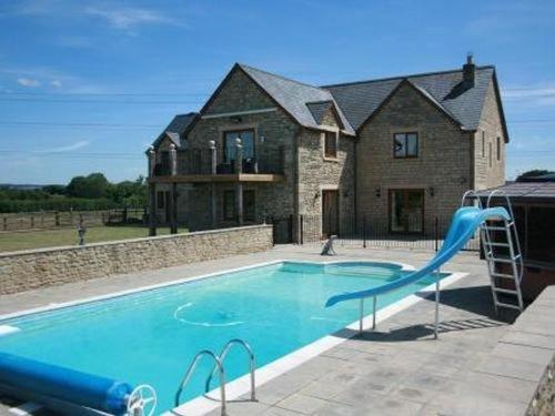 a swimming pool with a blue slide in front of a house at Whaddon Grove House in Melksham