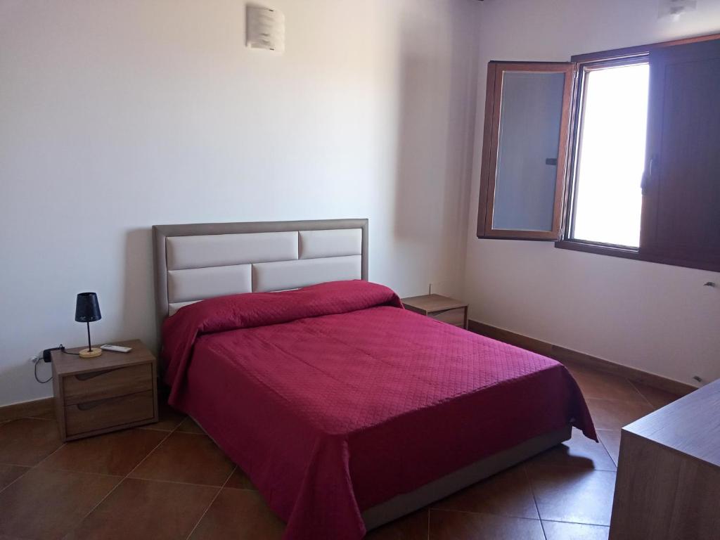 a bedroom with a bed with a red blanket and a window at CASA RURALE IMPASTATO in Montevago